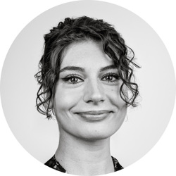 Livia Cadalbert. Livia is a young white woman with dark curly hair which she is wearing up. She is wearing a dark top with flowers on.