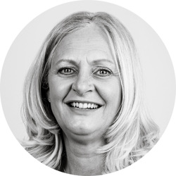 Denise McGrath. Denise is a white woman with long blonde hair. She is wearing a gold chain and is smiling.